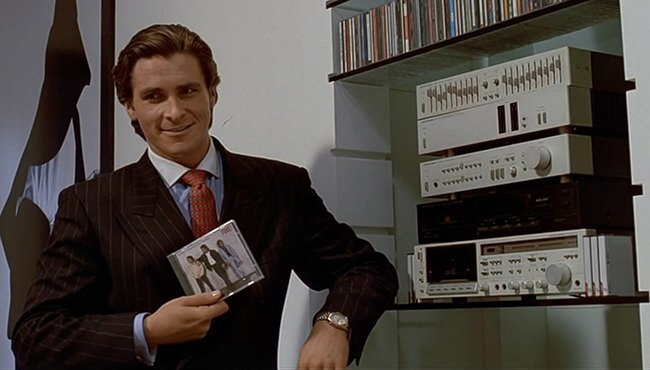 Patrick Bateman holding a cd and smiling.